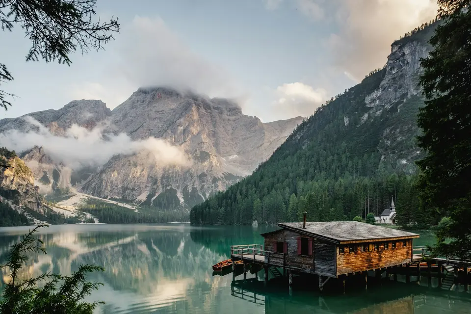 A small wooden cabin beside a still mountain lake